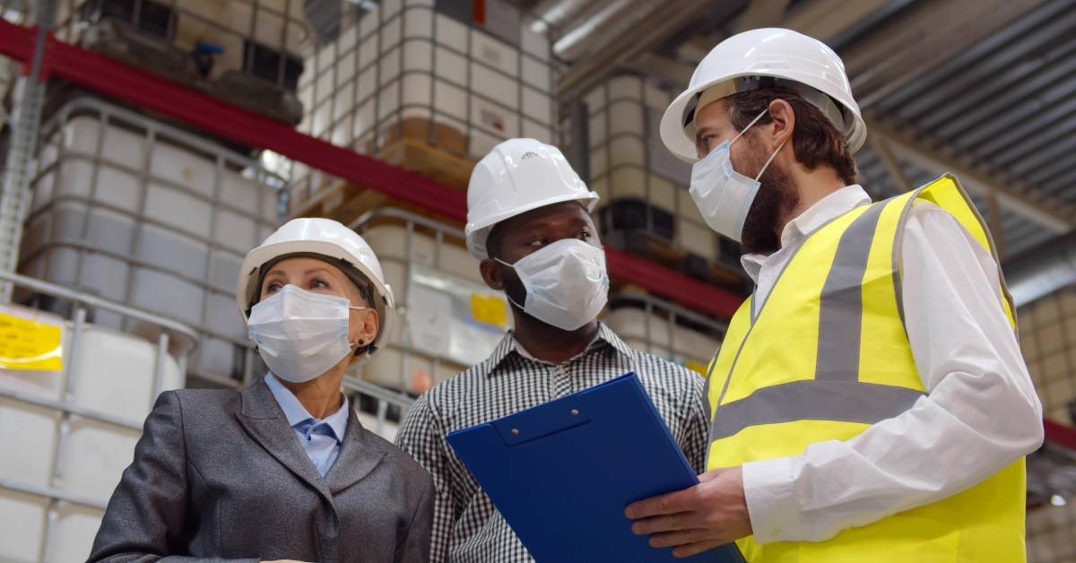 three health and safety managers discussing regulations in a warehouse