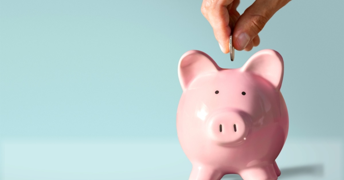 hand putting coin in piggy bank