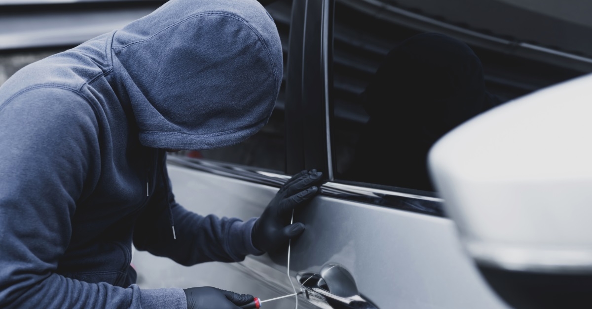 thief unlocking car door using screwdriver