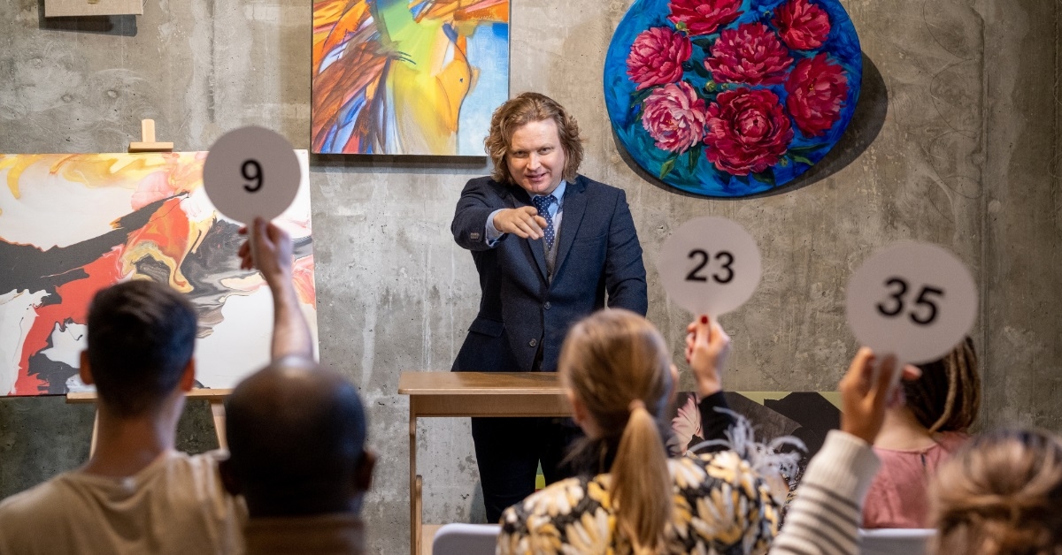 mature male auctioneer pointing at people