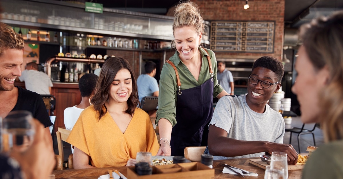 attractive waitress serving multi ethnic friends