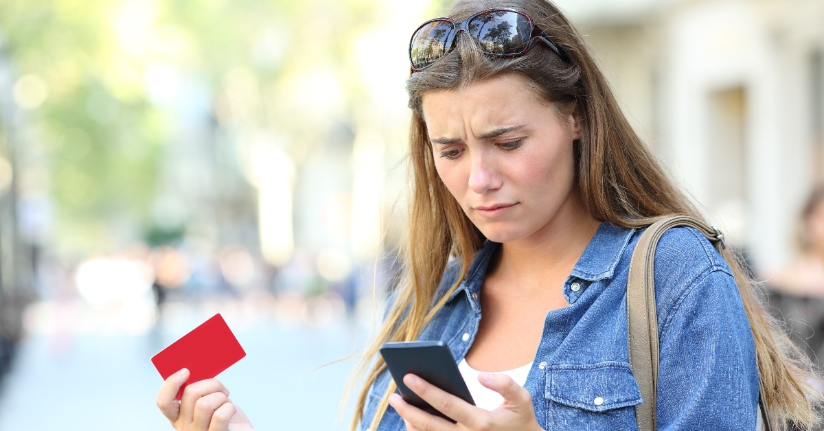 Woman with worried expression holding a credit card