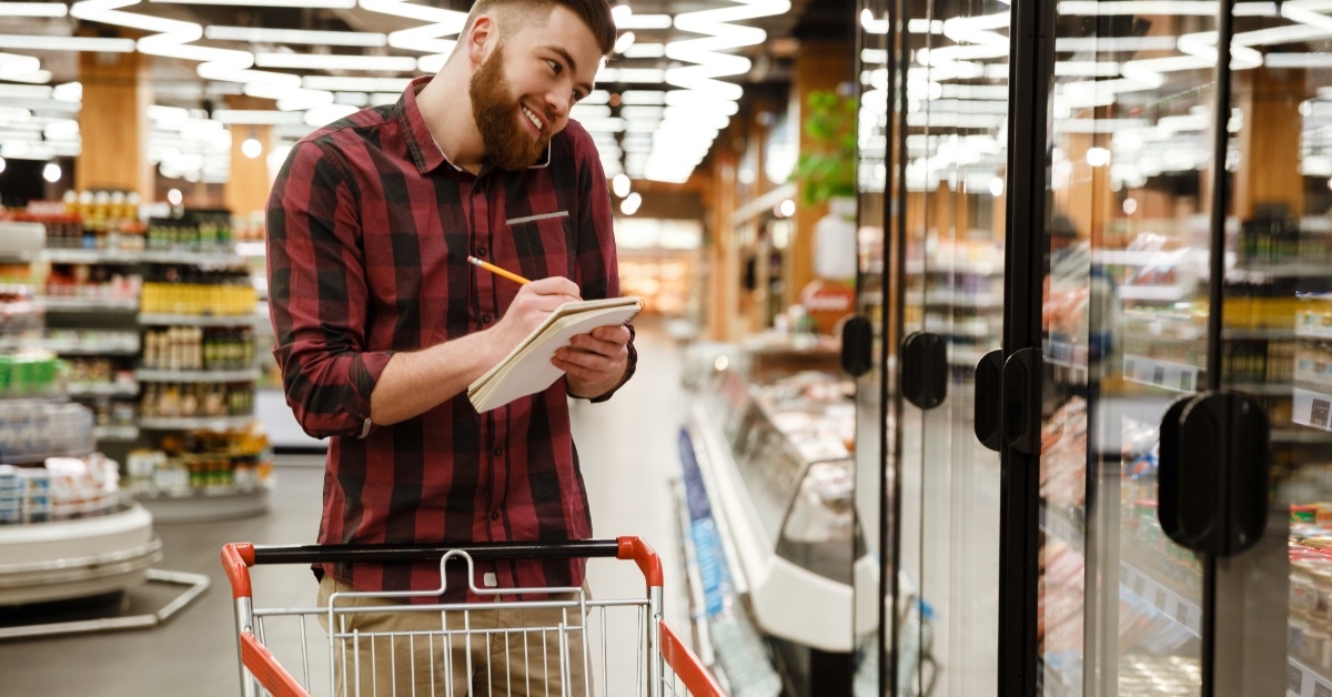 man writing notes while doing grocery