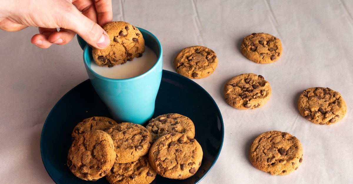person dipping cookie in milk cup
