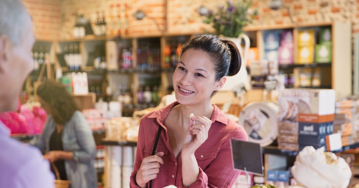 woman sampling cheese at deli counter