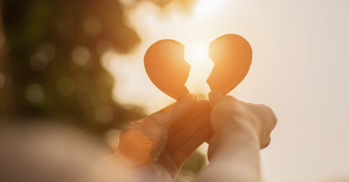hand holding broken heart pieces outdoors