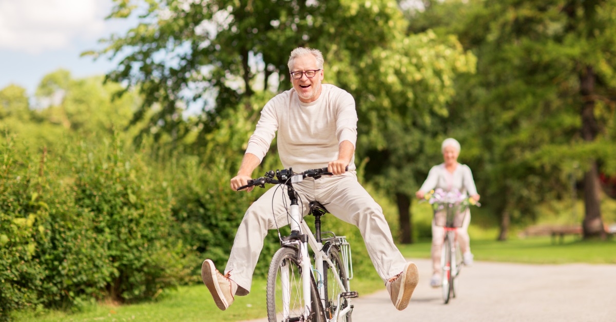 happy senior couple riding bicycle outdoors