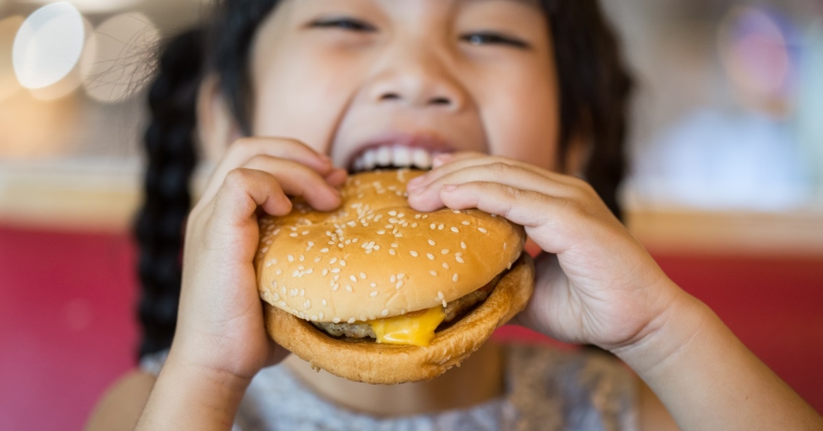 asian girl eating cheeseburger