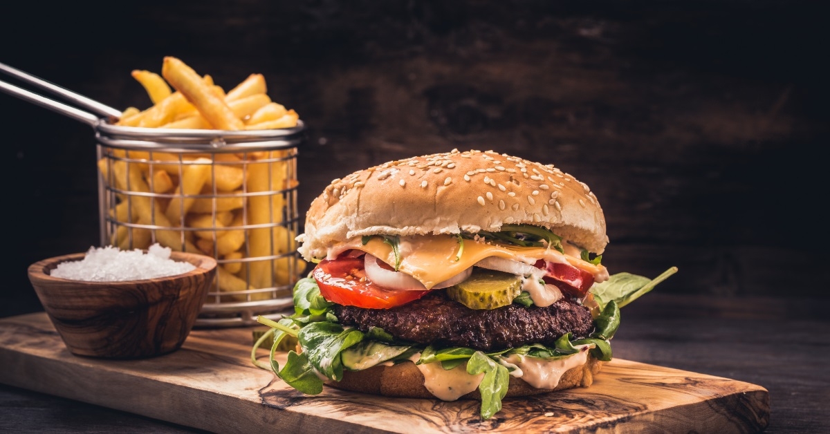 Burger with fries on wooden board
