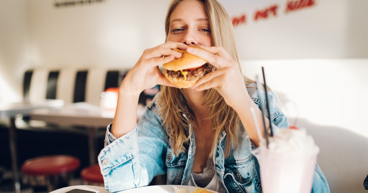woman eating burger in restaurant