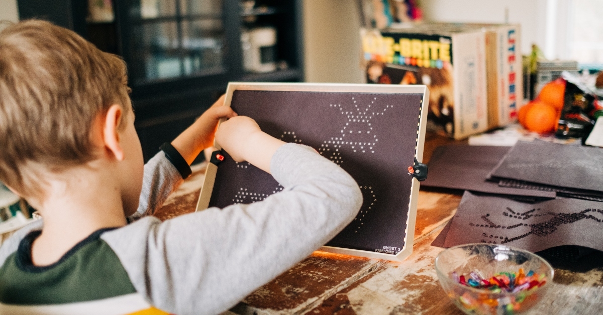 young boy playing lite brite