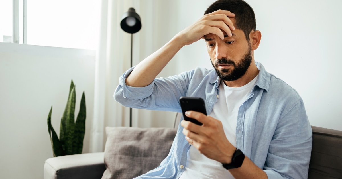 shocked man scrolling smartphone at home