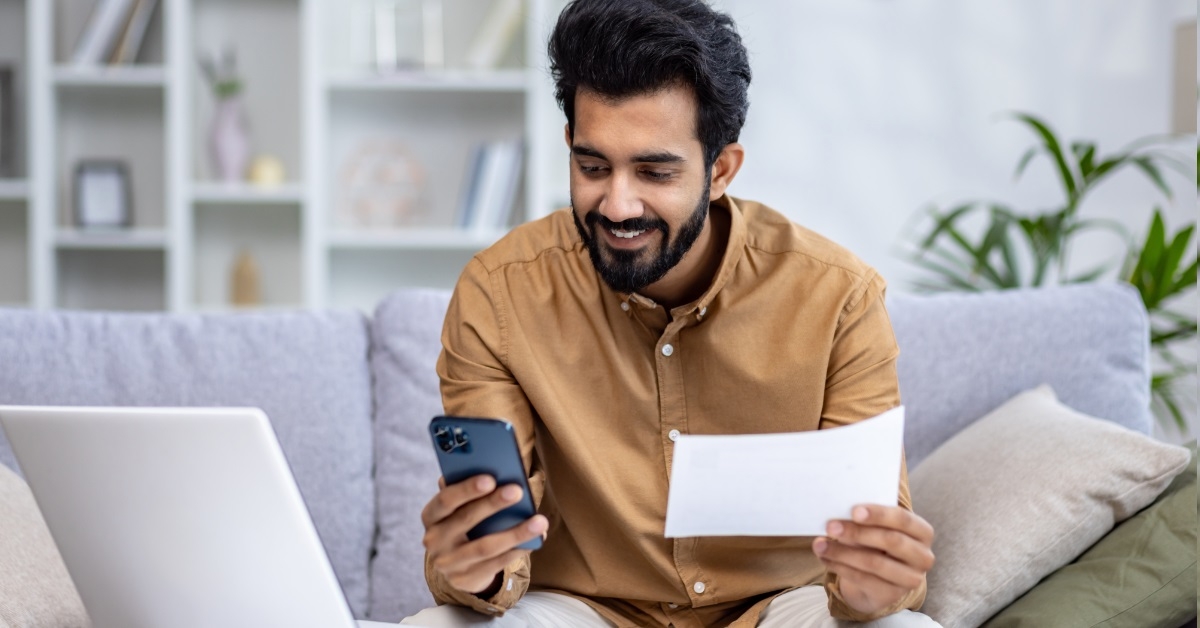 happy man reviewing bills using smartphone