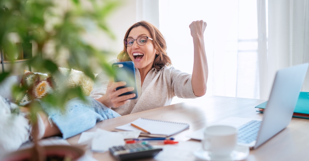 woman cheering while using smartphone