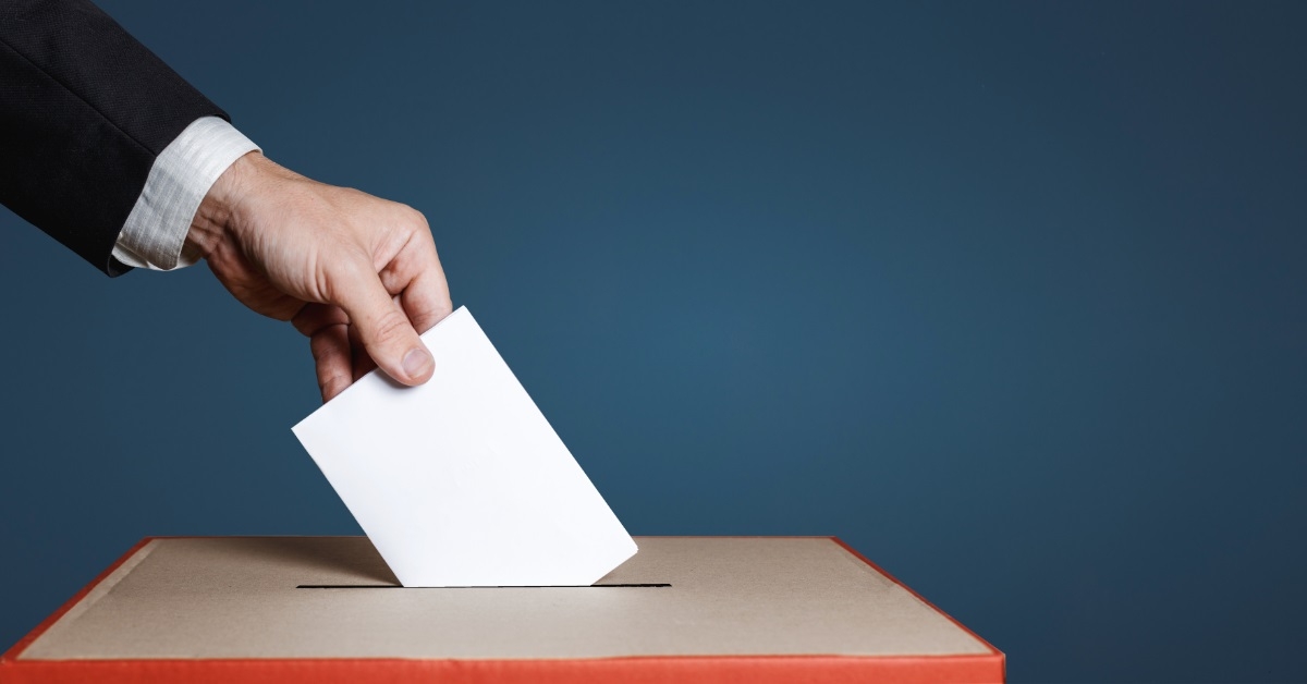 hand inserting envelope in ballot box