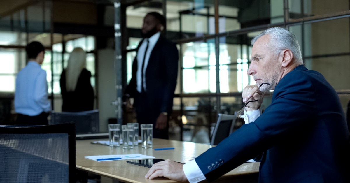 Unhappy senior boss sitting at office