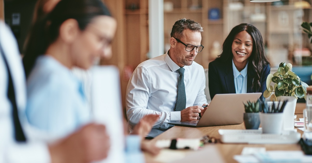 colleagues using laptop together at work