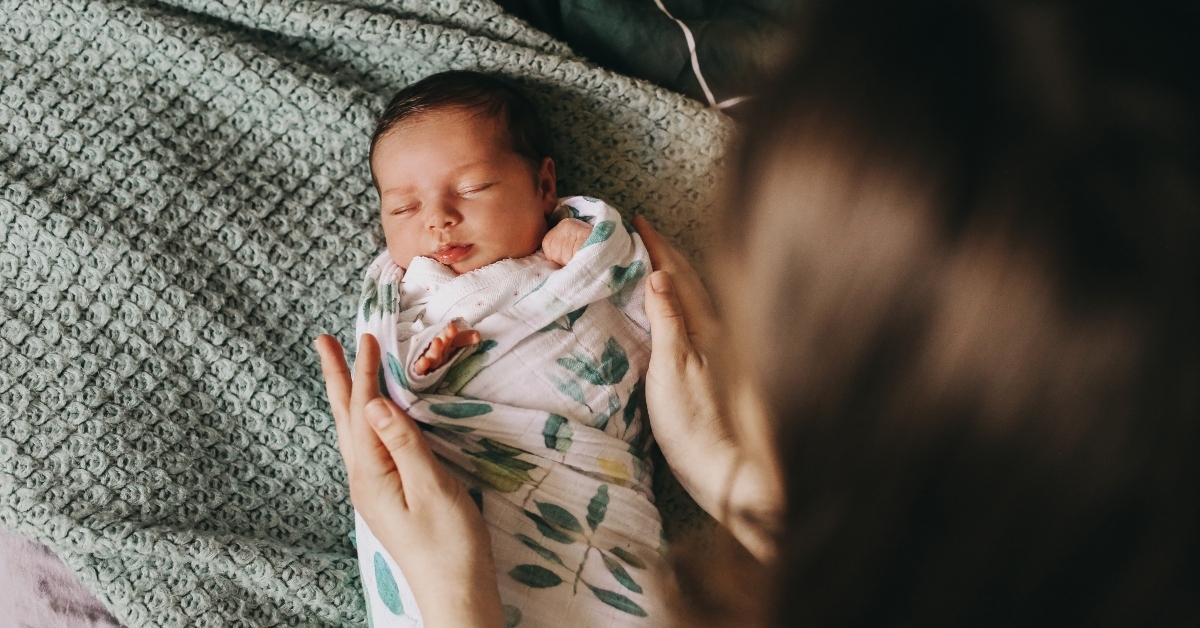 mother swaddling a newborn baby