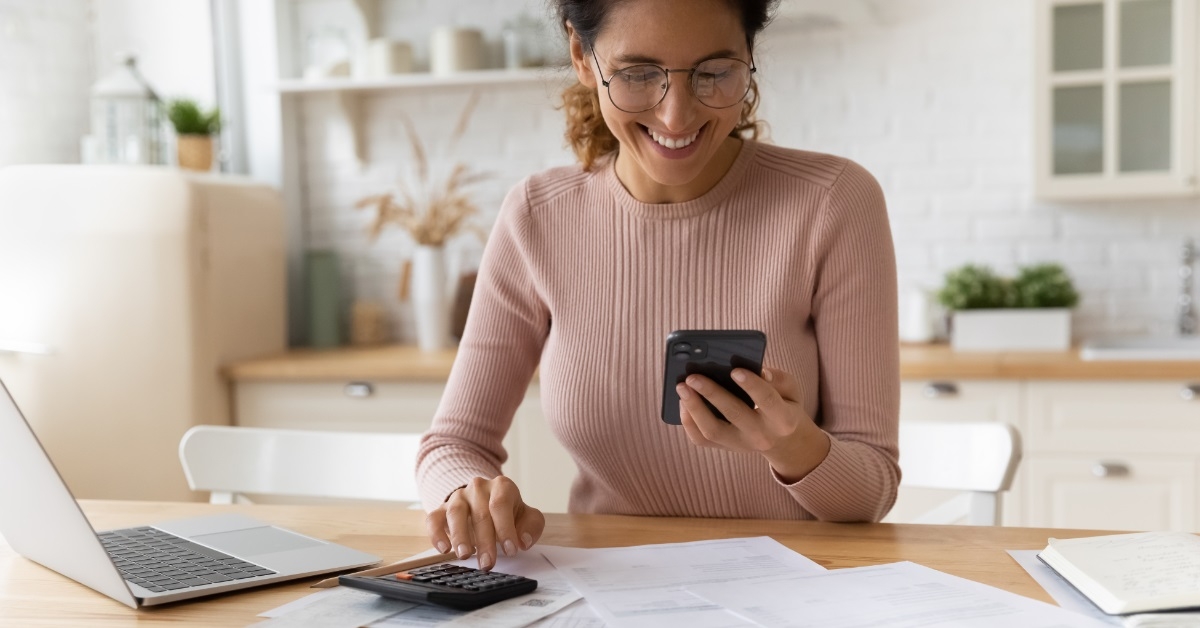 happy woman reviewing bills using phone