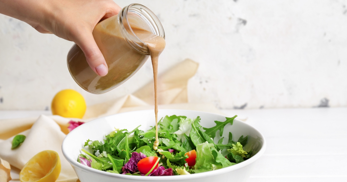pouring tahini onto salad bowl