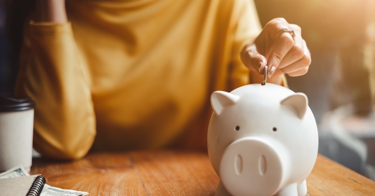 hand putting coin into piggy bank