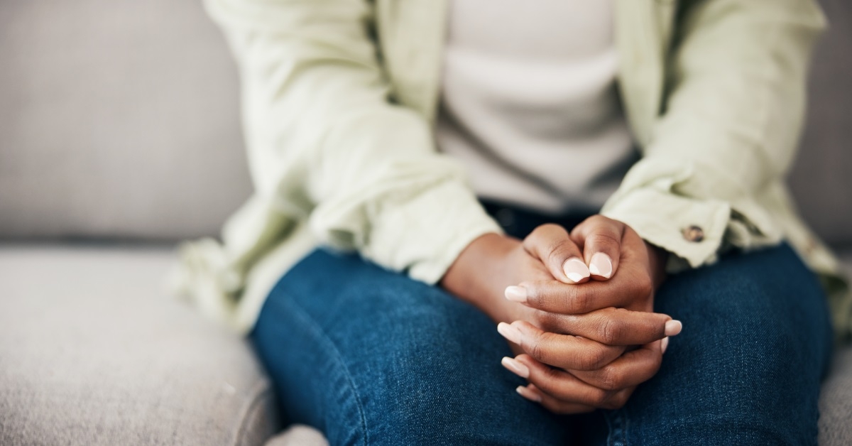 anxious woman folding hands on couch