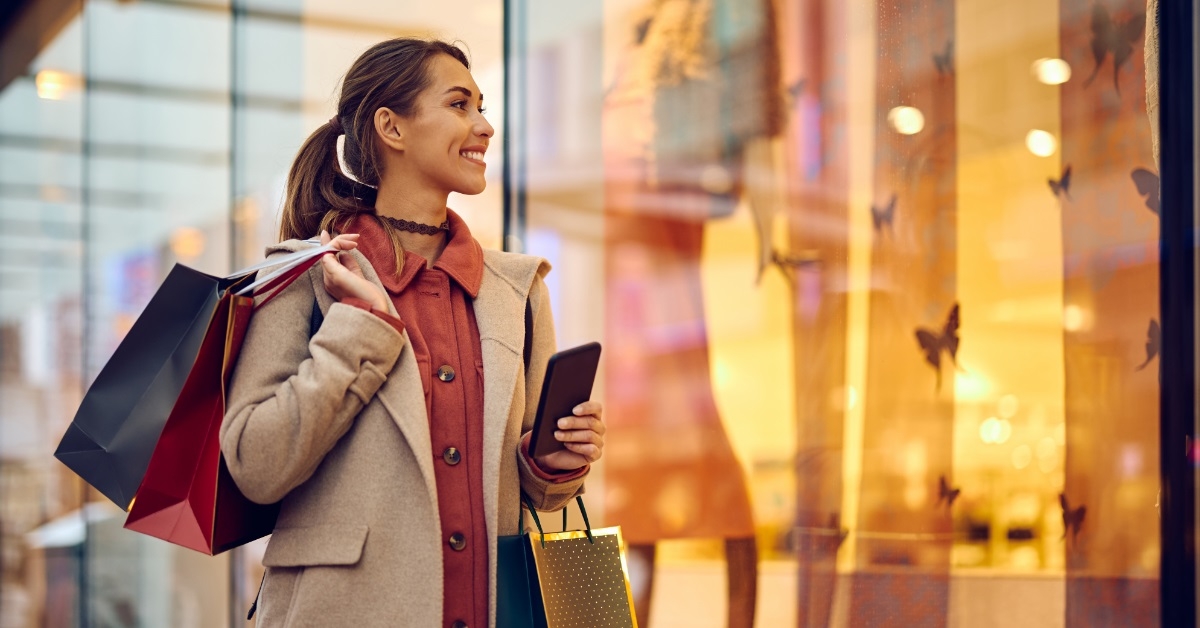 woman with shoppers staring store windows