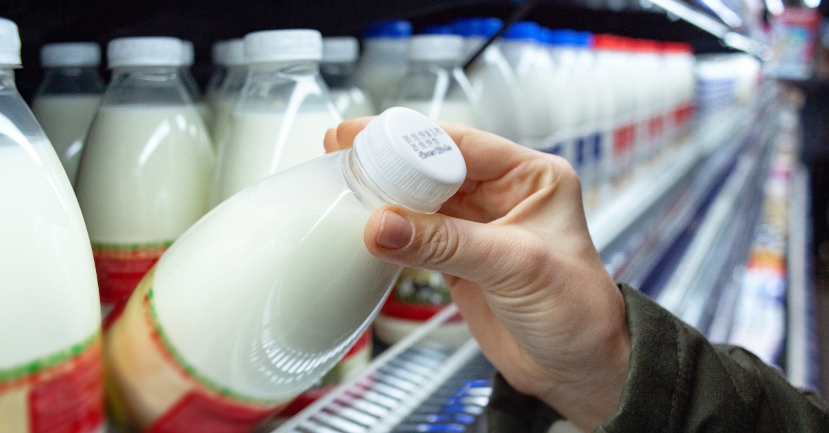 woman holding milk bottle in supermarket