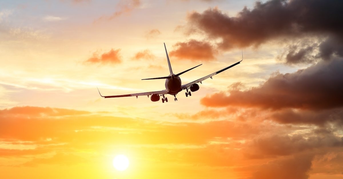 Commercial airplane flying above dramatic clouds during sunset