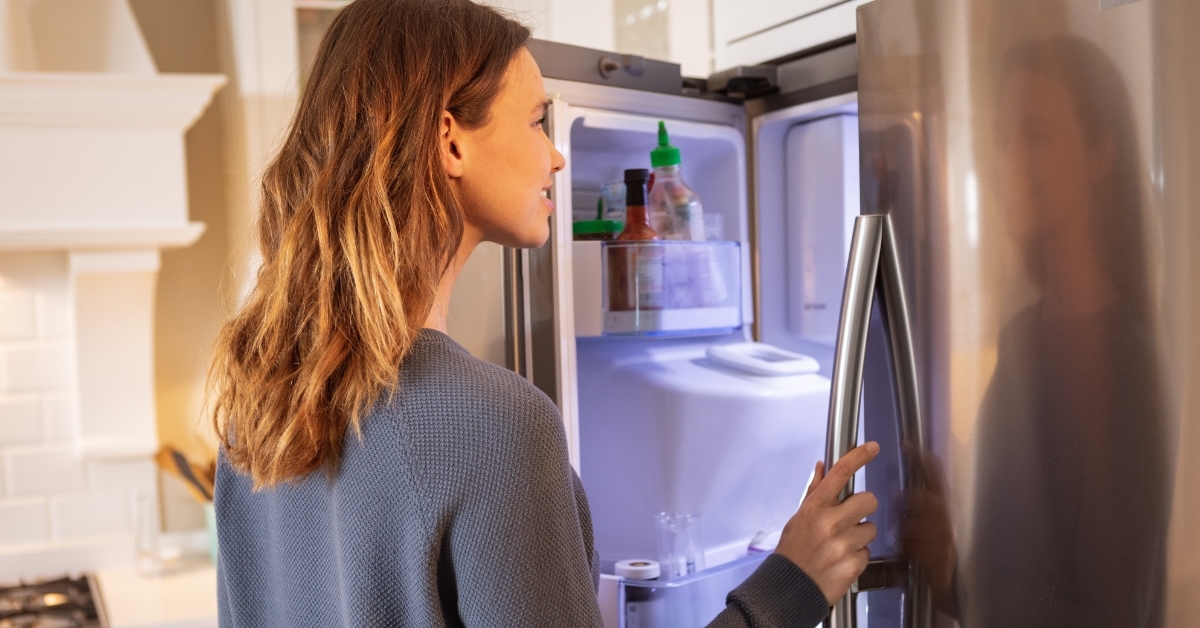 woman searching for food in refrigerator 
