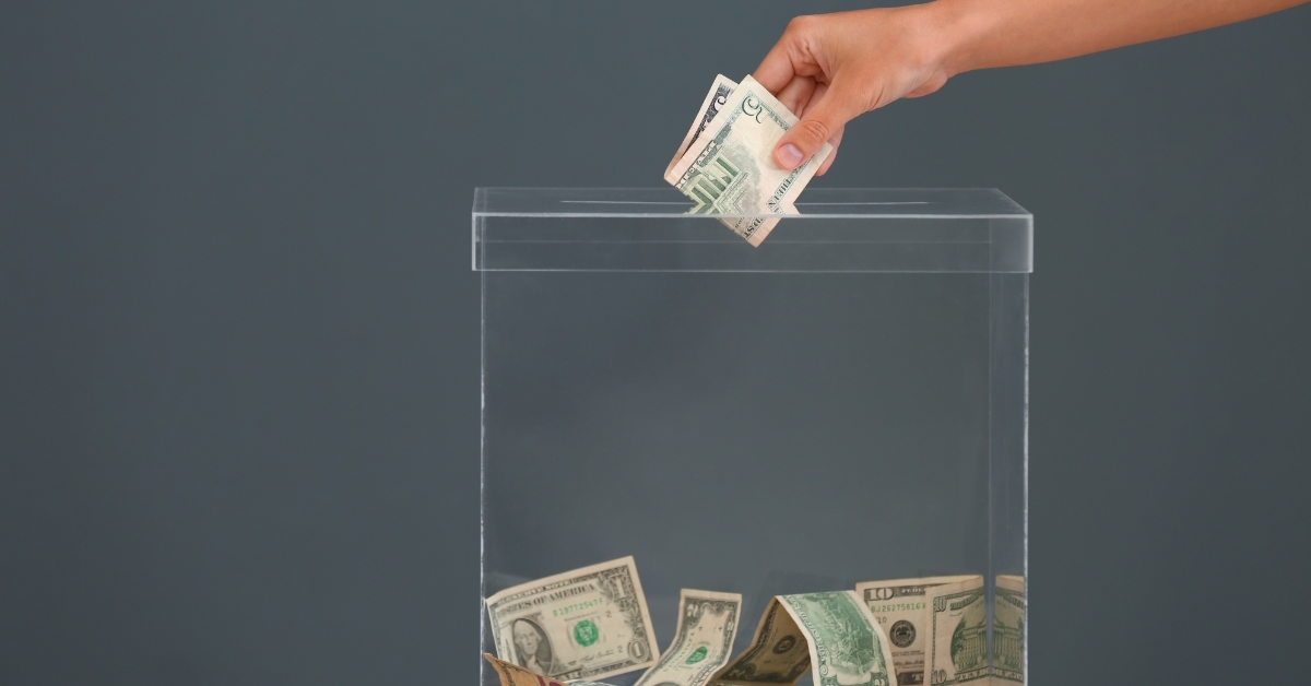 Woman putting money into donation box on table