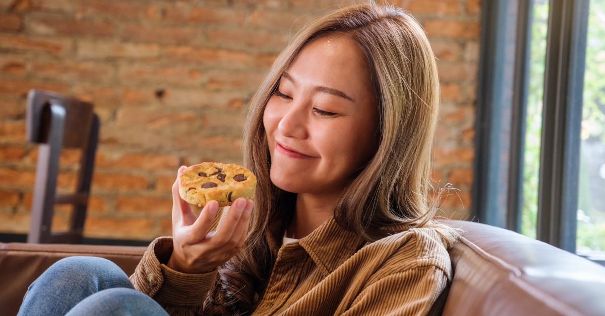 asian woman eating piece of cookie