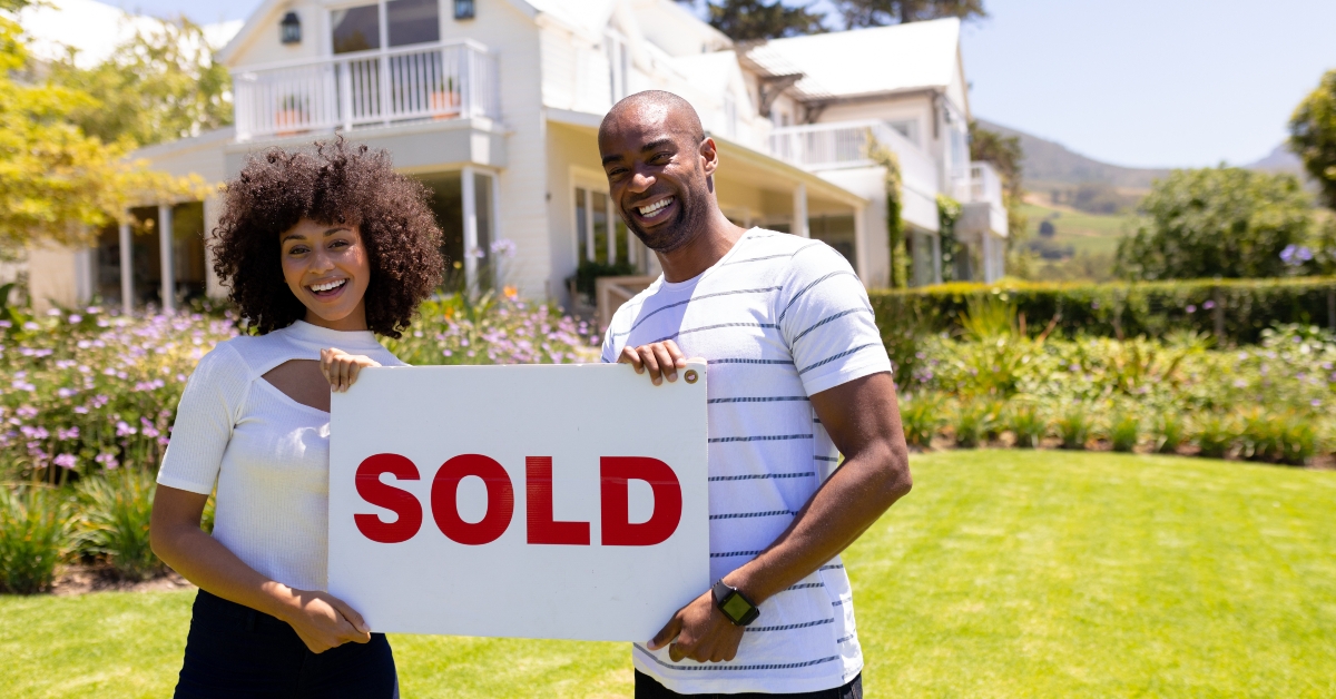 happy couple holding sold sign