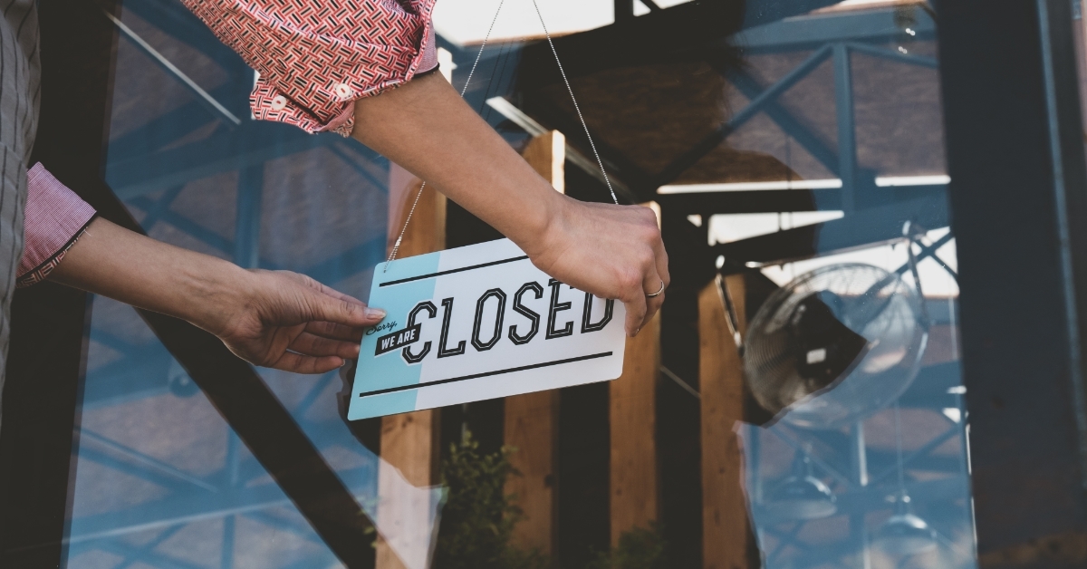 woman placing closed sign at entrance