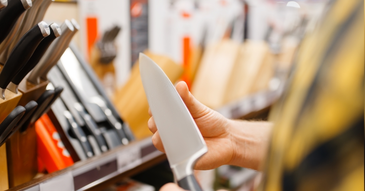 man choosing kitchen knife at store