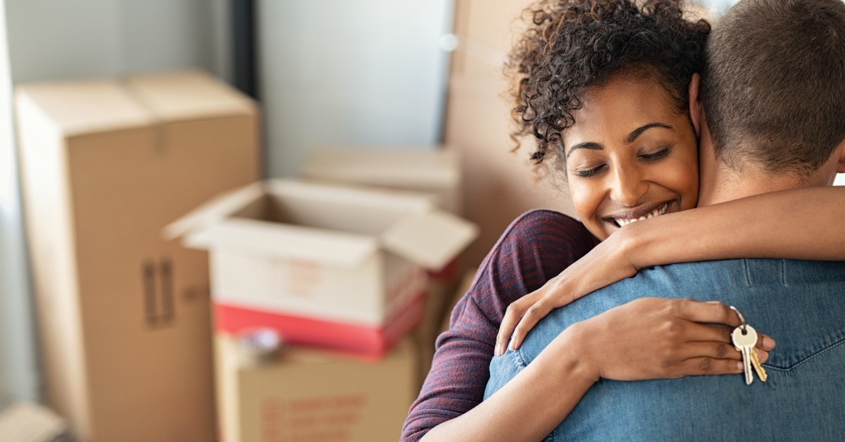 wife hugging husband with home keys