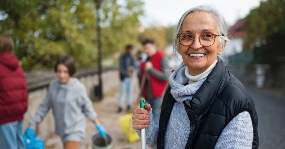 cheerful senior female volunteer cleaning street
