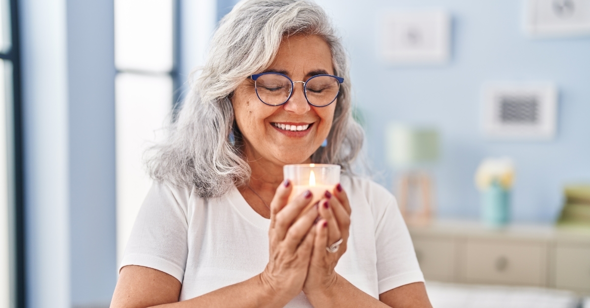 woman smelling aromatic candle at home