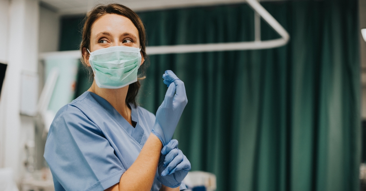 Nurse wearing gloves in hospital room