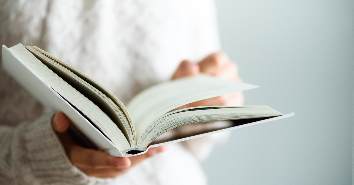 girl reading book in white jumper