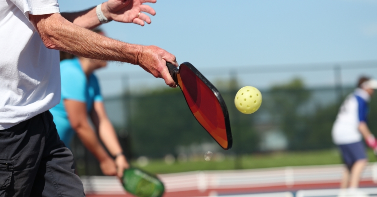 senior man playing Pickleball on field