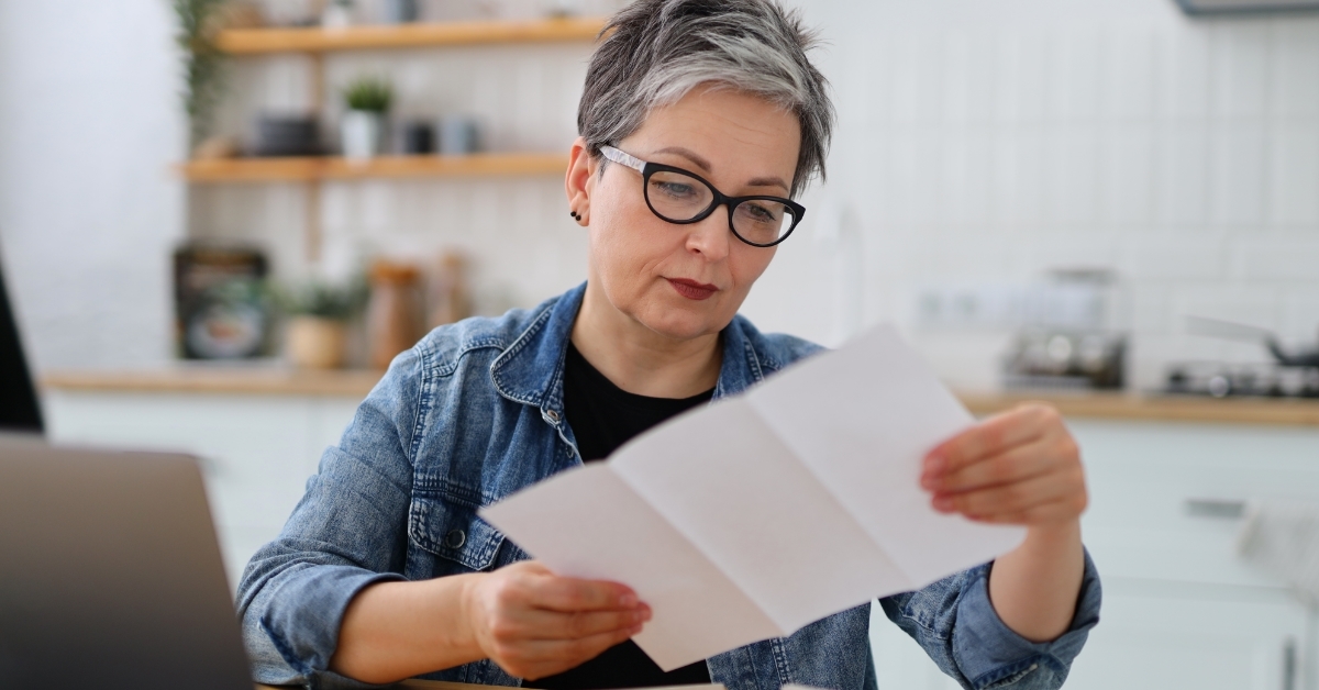 senior woman reviewing bills in kitchen 