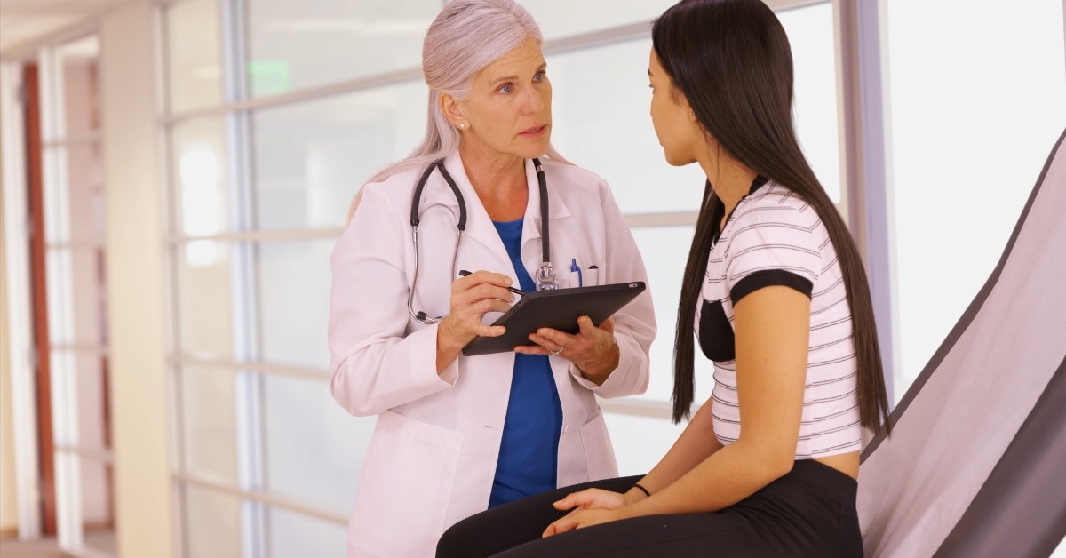 doctor holding tablet checking young girl 