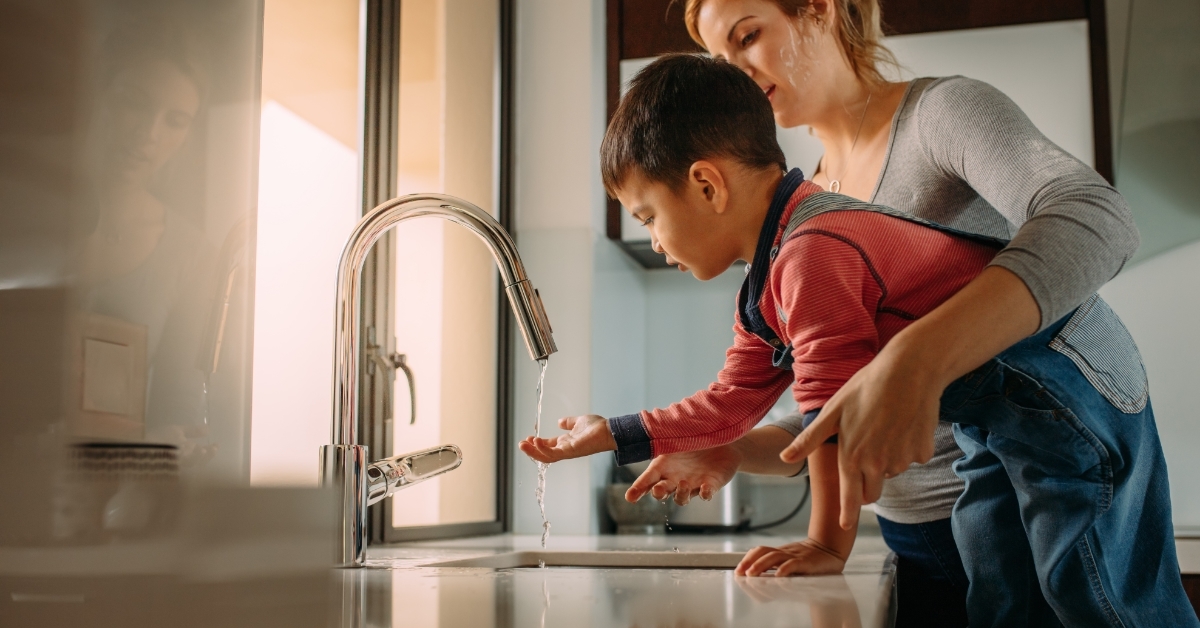 boy with mother using kitchen sink