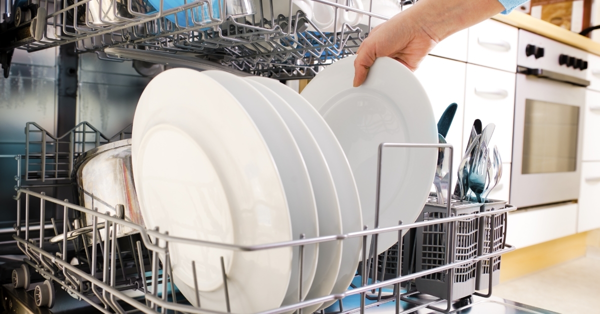female hands loading dishes to dishwasher