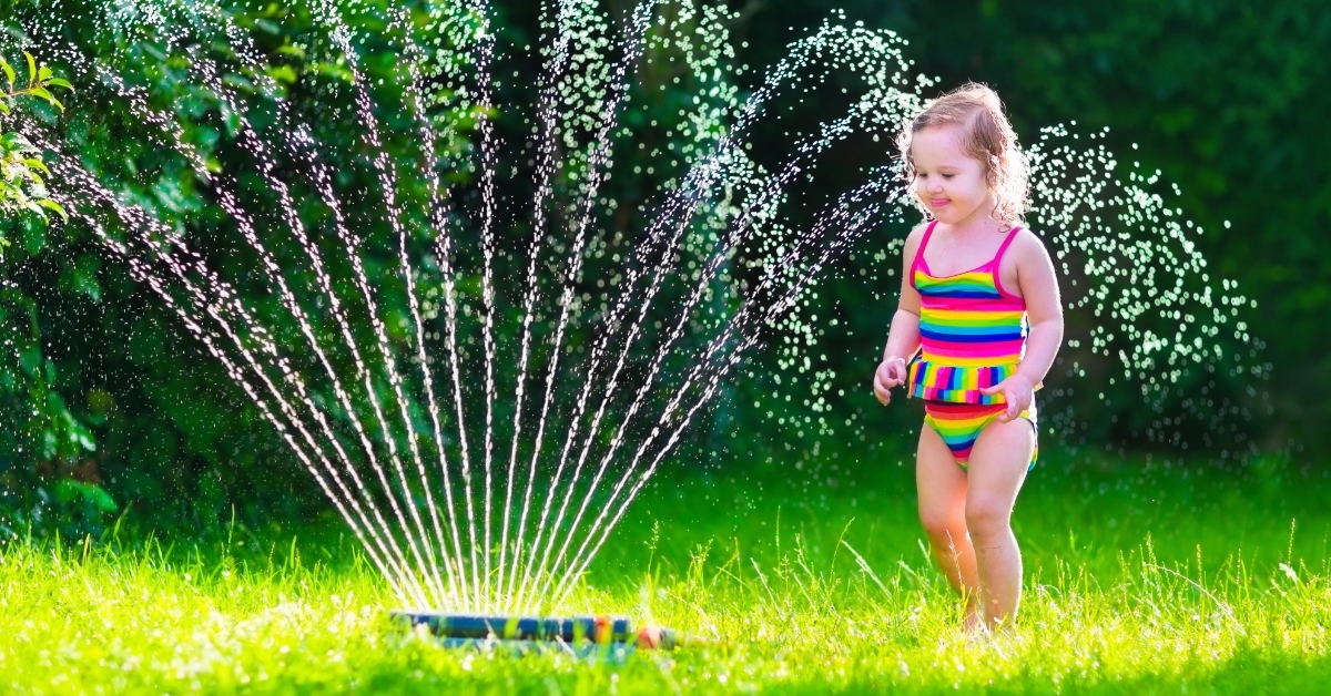 girl playing with garden water sprinkler