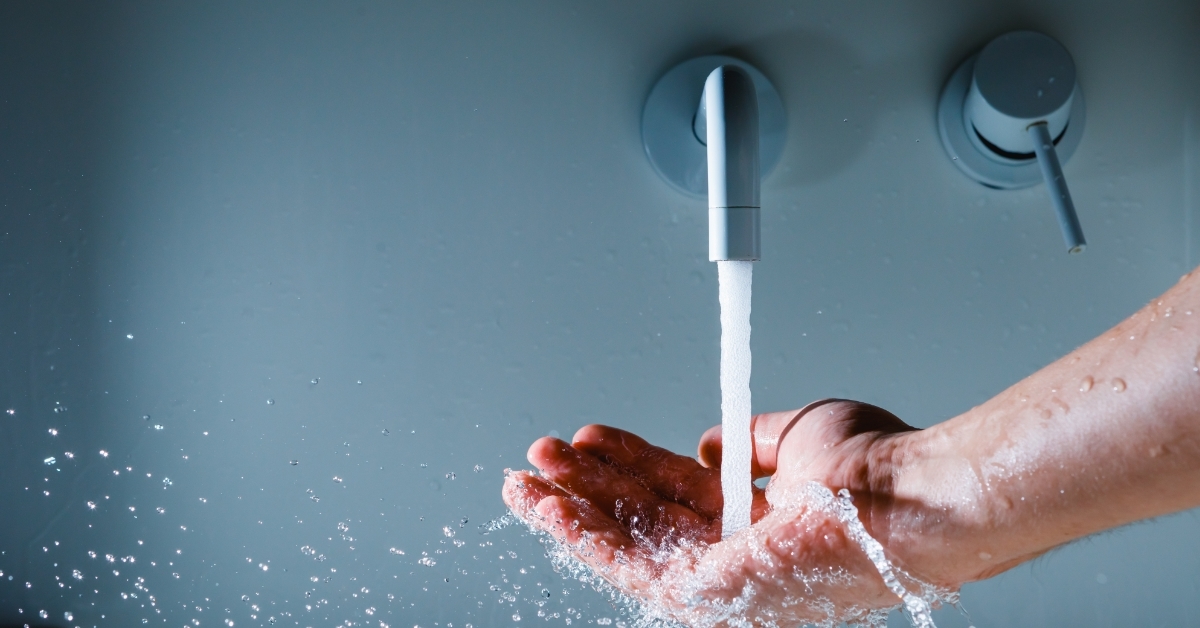 hand under faucet with flowing water