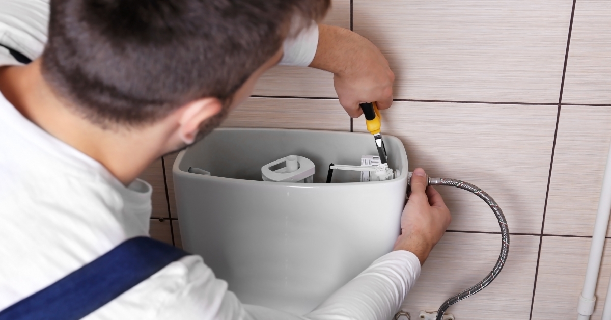 male Plumber repairing toilet cistern