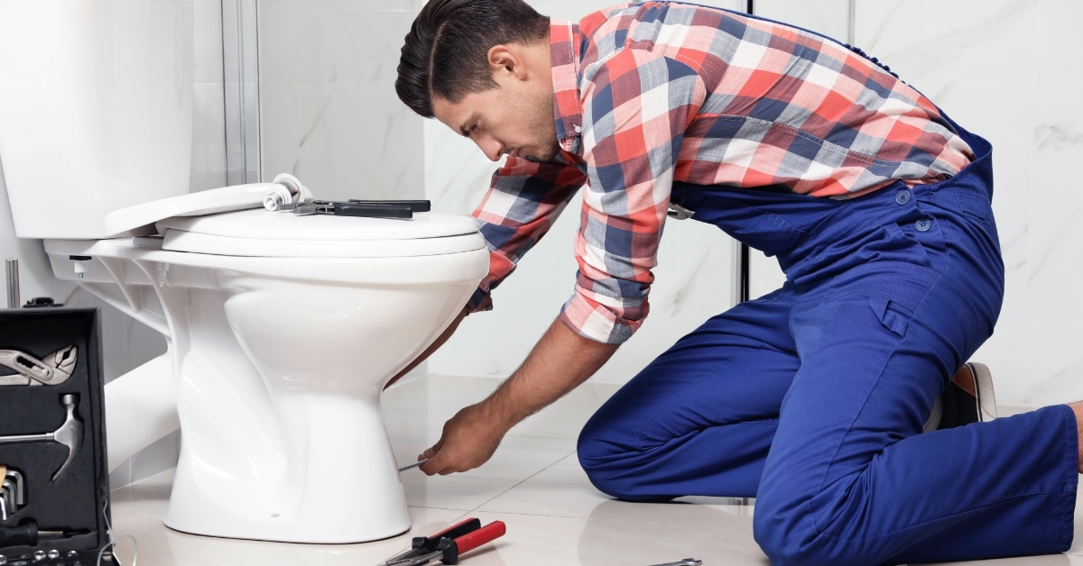 plumber working with toilet bowl