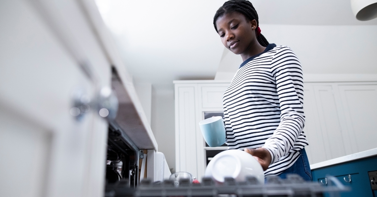 woman Stacking Crockery In Dishwasher